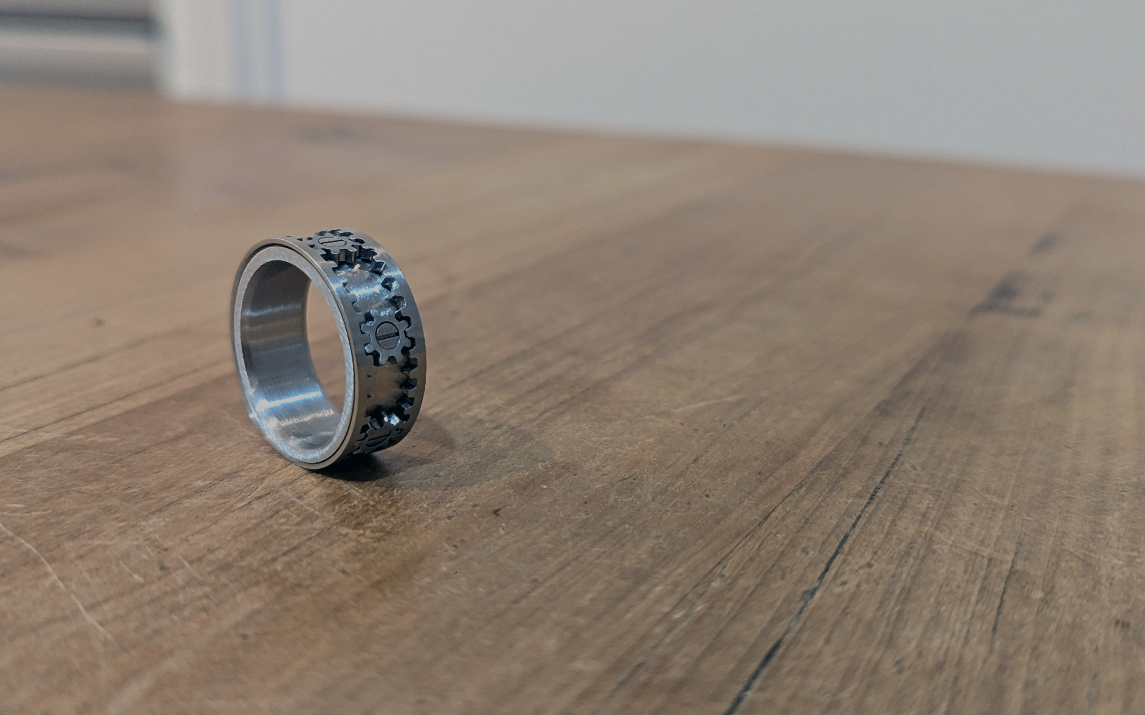 Stainless Steel Cogwheel Fidget Ring on a wooden table